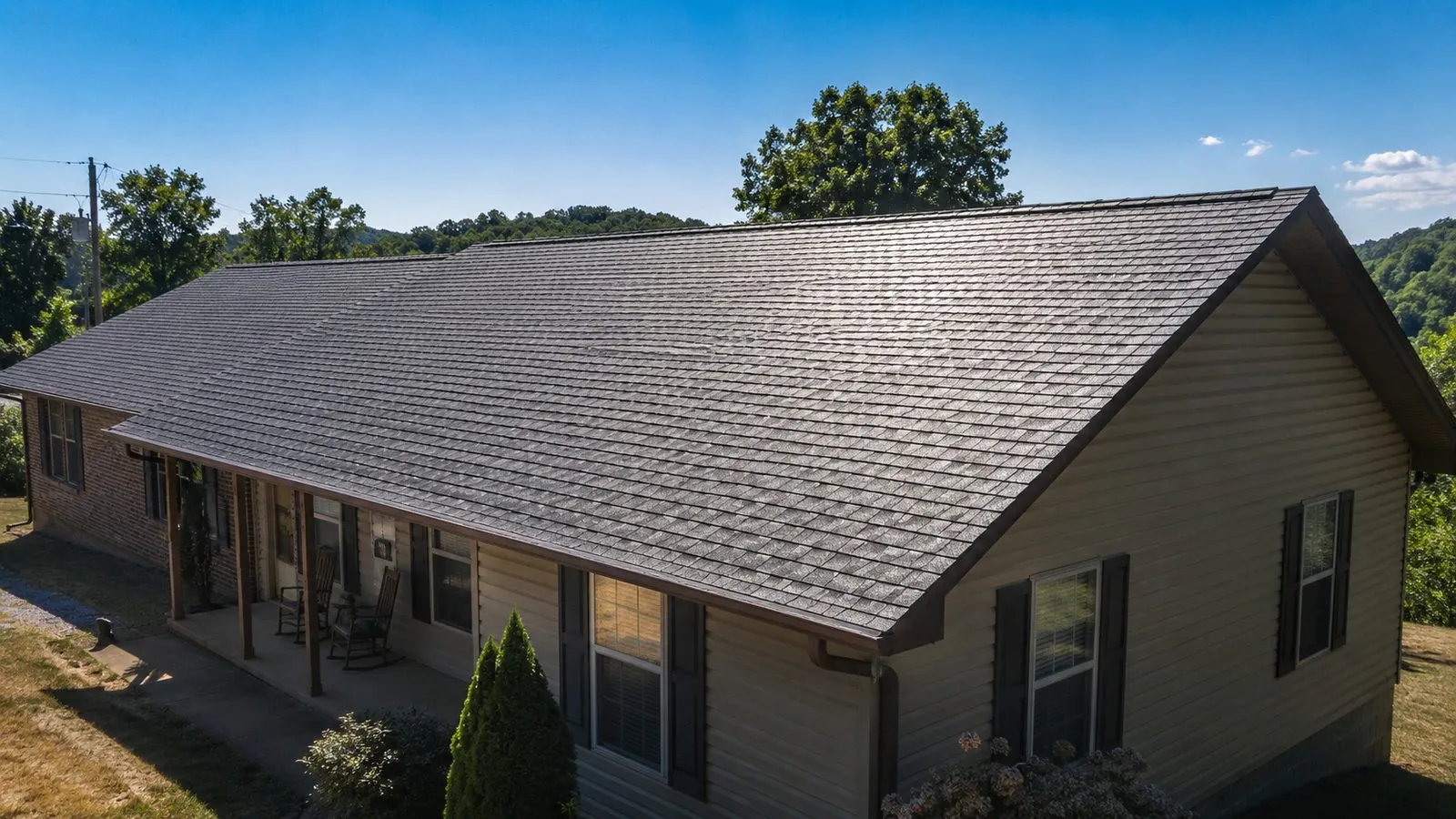 Sun beating down on the dark asphalt shingle roof of a western Kentucky ranch home on a clear summer day