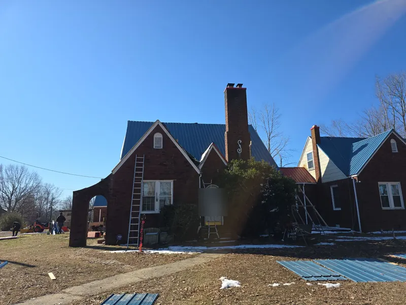Brick Tudor-style home in Lynn Grove, KY with its new blue metal roof, ladders still up