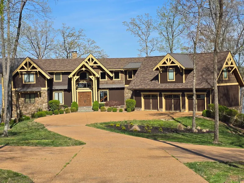 Large timber-accented lakeside home near Aurora, KY with an architectural shingle roof and metal accent roofs