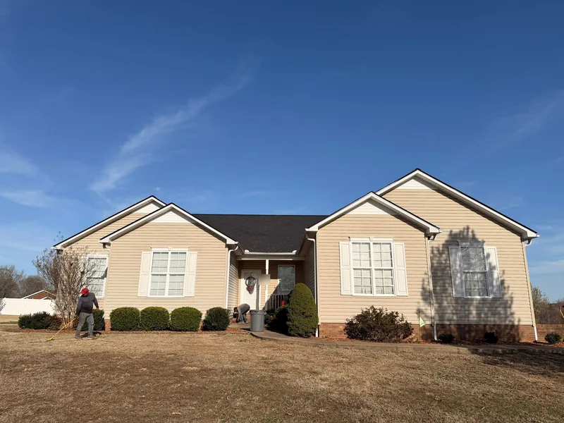 Vinyl-sided ranch home in Paris, TN with a new dark architectural shingle roof as the crew cleans up the yard