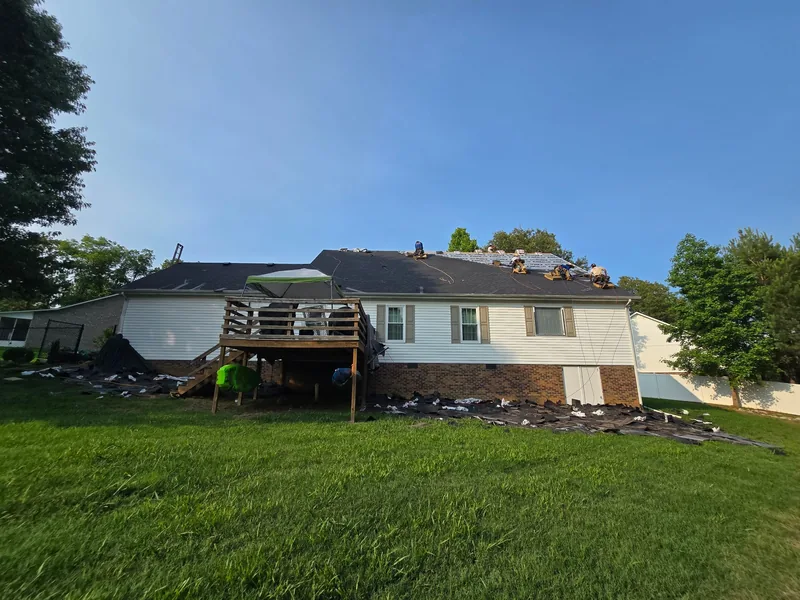 Fit Roofing crew laying underlayment and new shingles on a ranch home in Paris, TN, with tear-off debris on tarps below