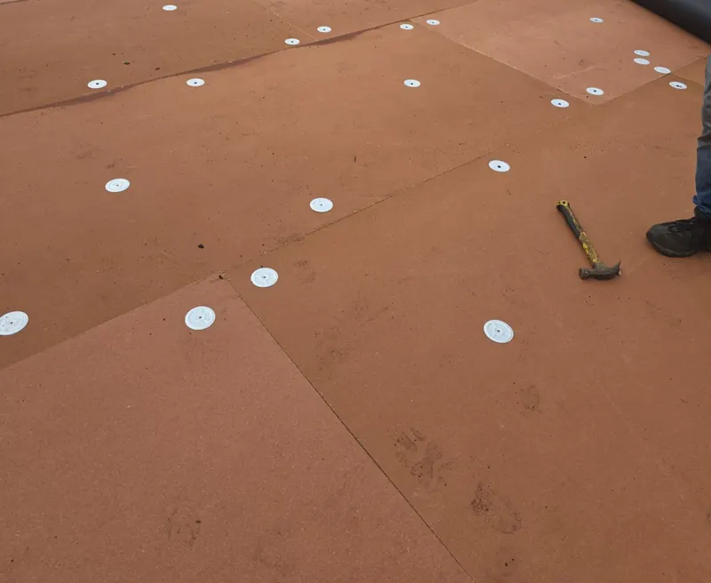 Cover board fastened down with round plates on a commercial flat roof in Benton, KY, before the membrane goes on