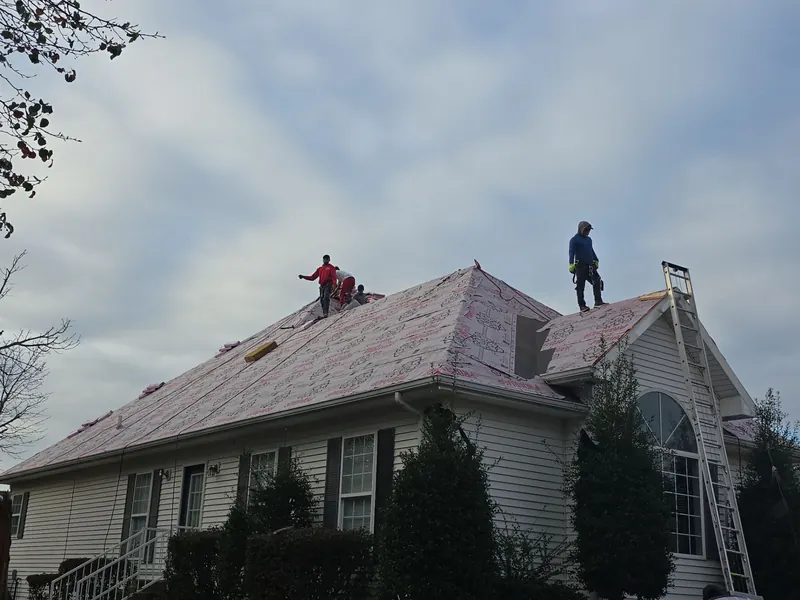 Roofing crew working over synthetic underlayment on a hip roof in Lone Oak, KY