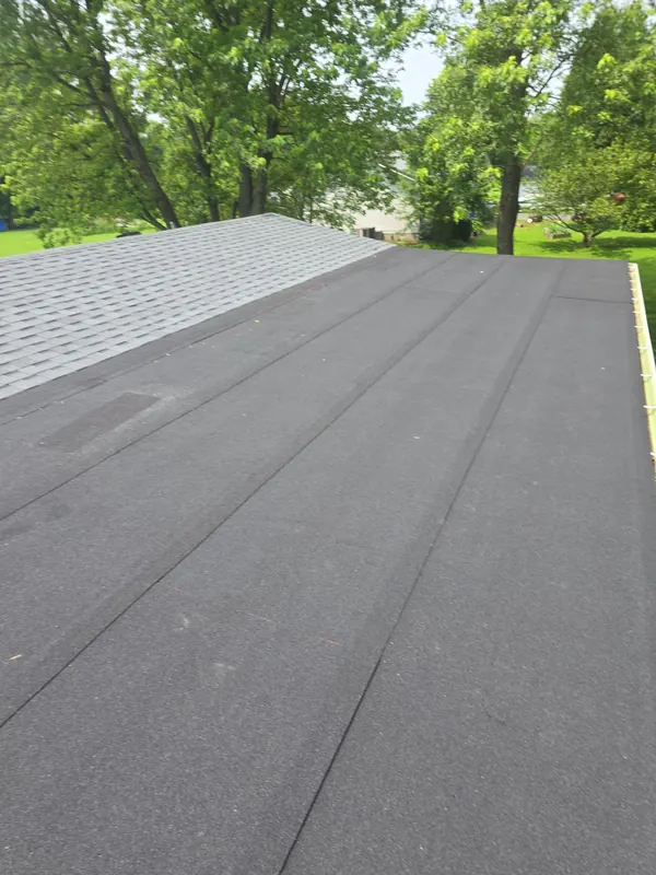Dark base sheet rolled out on a low-slope roof section beside new gray shingles in West Paducah, KY