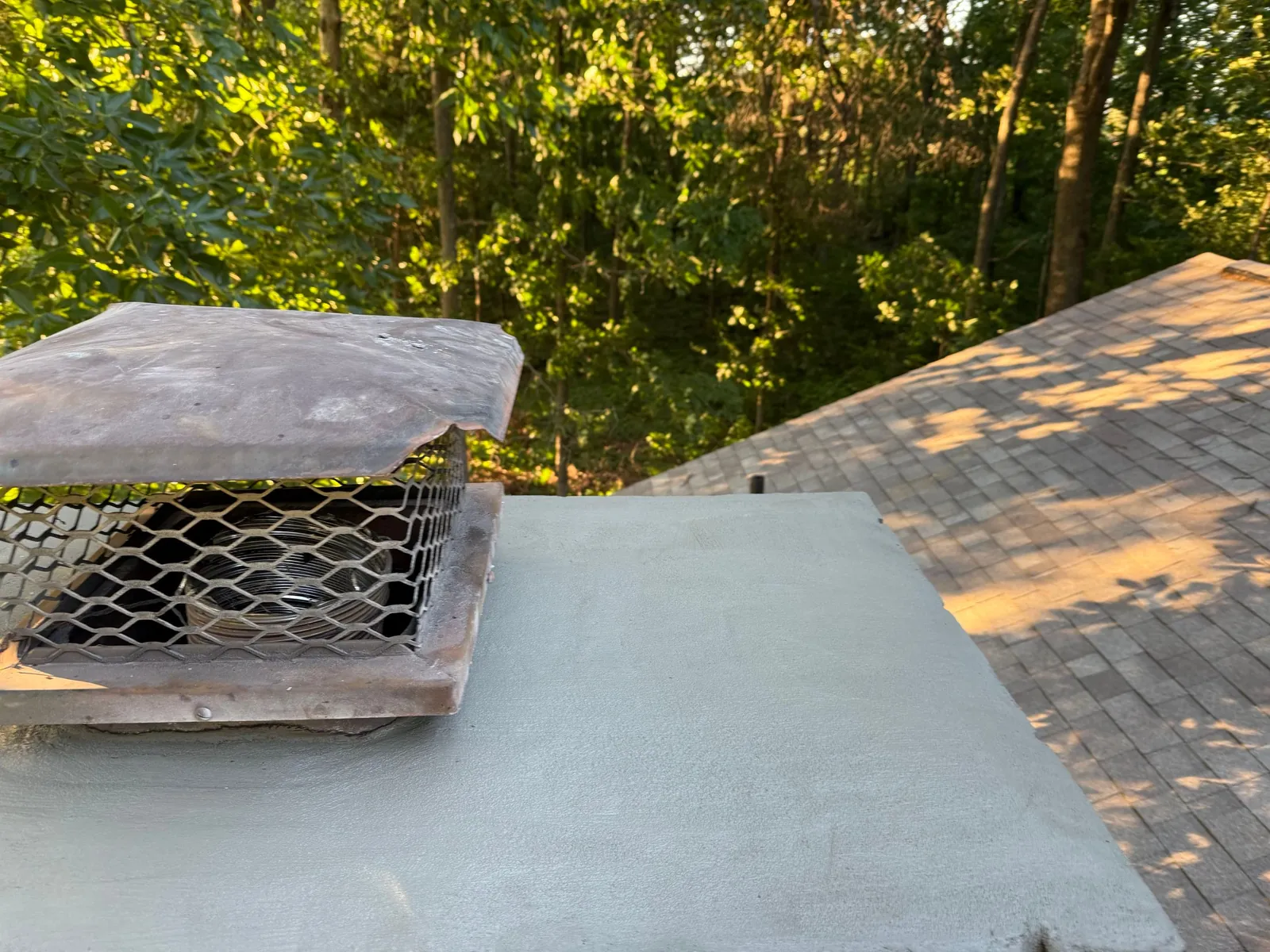 New smooth cement crown around the chimney cap, with the shingle roof beside it