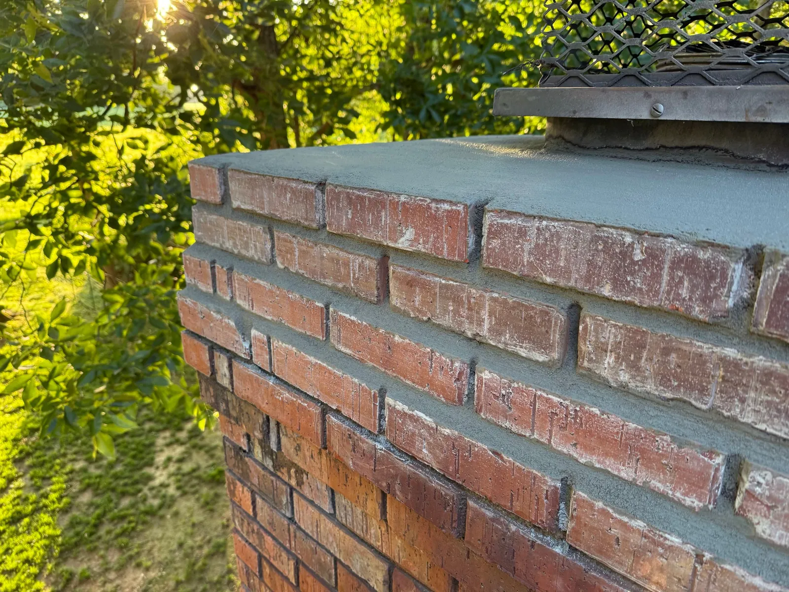 Repaired chimney with fresh mortar in the brick joints and a new cement crown