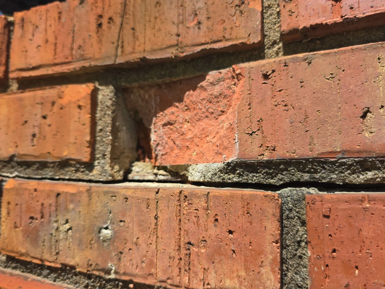 Close-up of spalled chimney brick and crumbling mortar joints