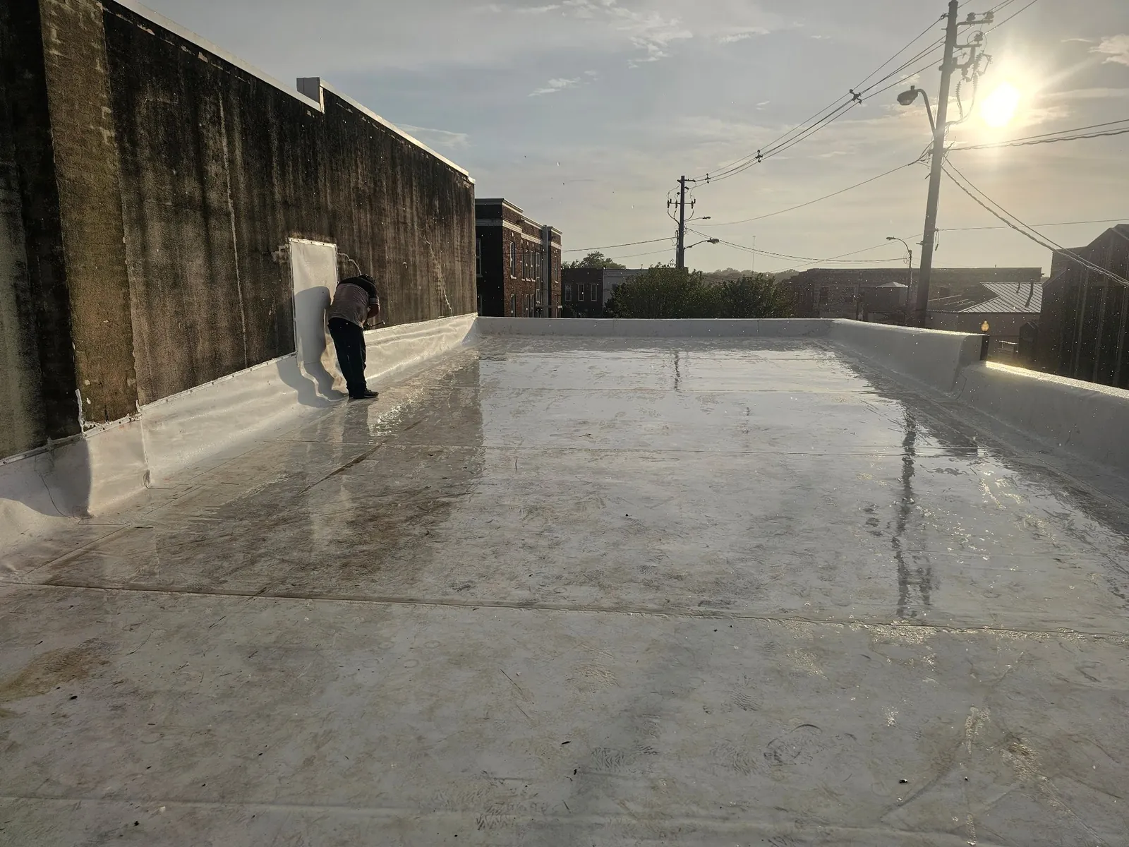 The new white membrane roof in evening light, with flashing run up the masonry wall