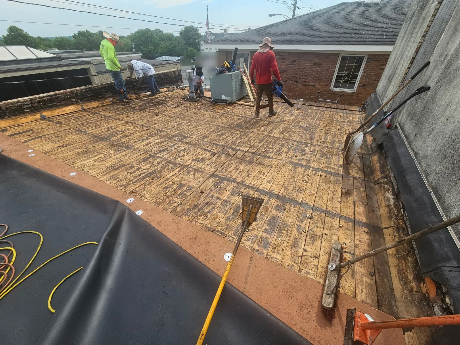 Crew removing the old roofing down to the wood deck on the commercial flat roof