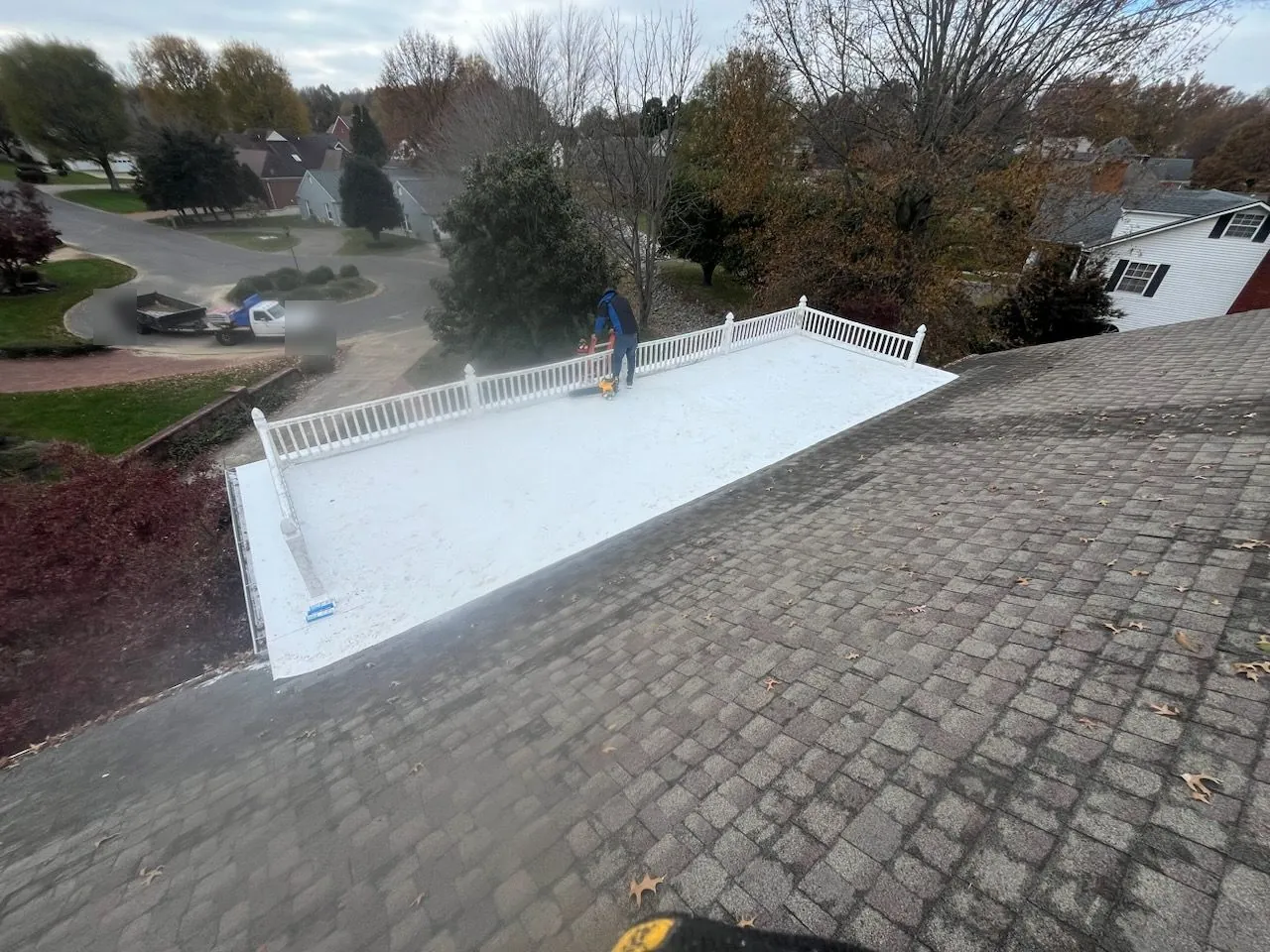New white single-ply membrane on the railed flat roof deck, with a crew member at the far end
