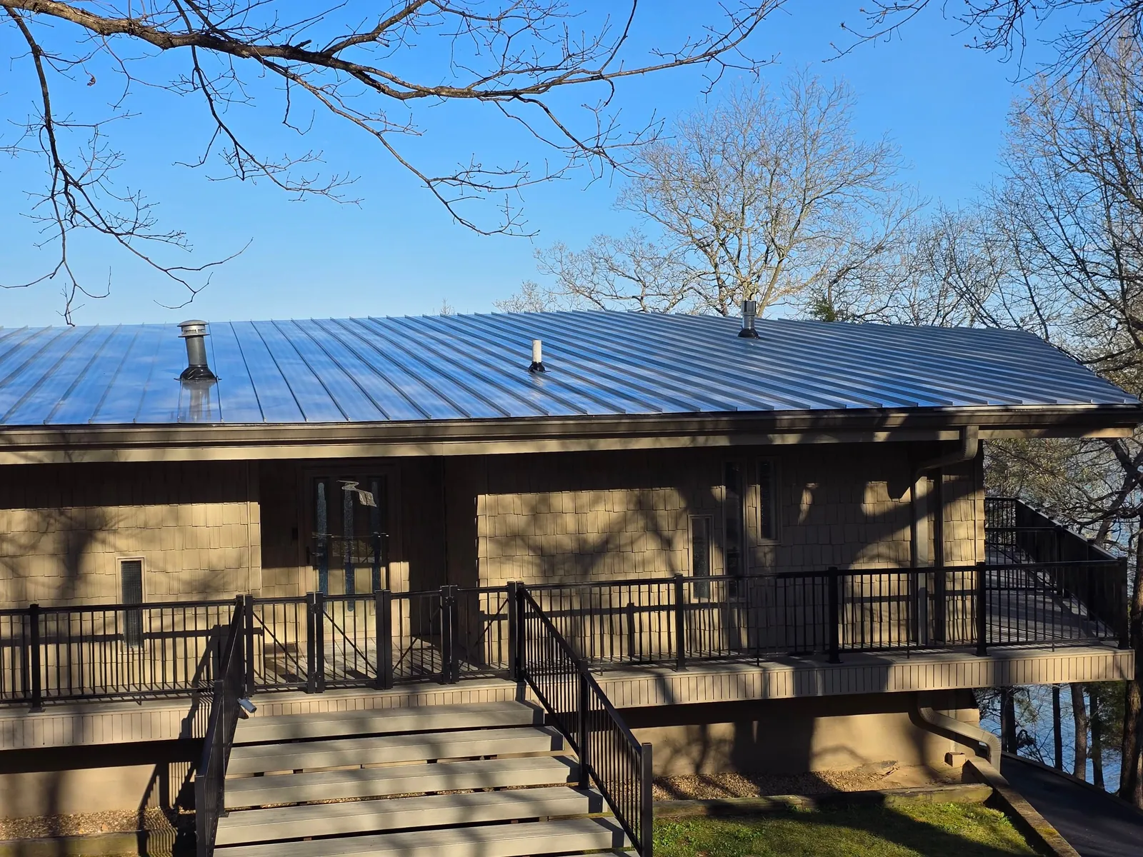 Lakeside home with its new light gray standing-seam metal roof, seen from the front steps