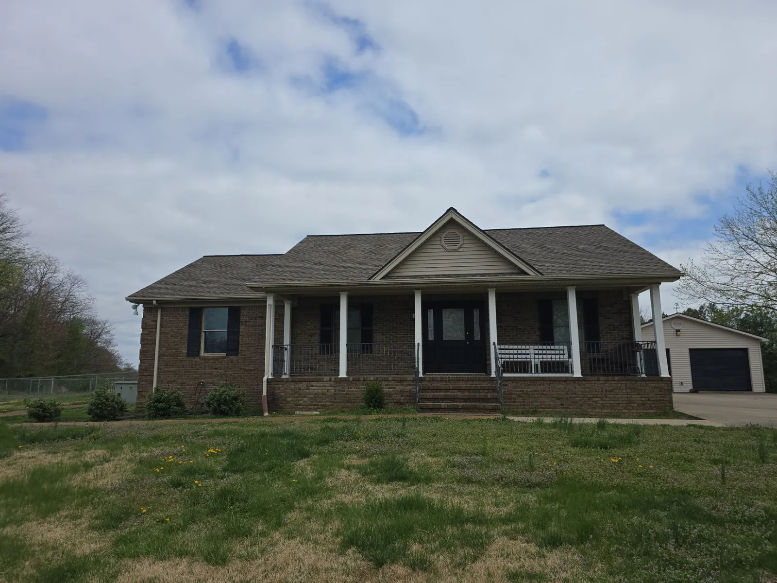 Brick ranch home in Lone Oak, KY with a covered front porch and its original shingle roof, before replacement