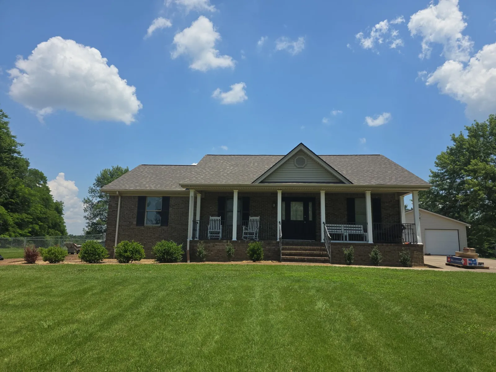 Front view of the brick ranch home and covered porch with the new architectural shingle roof