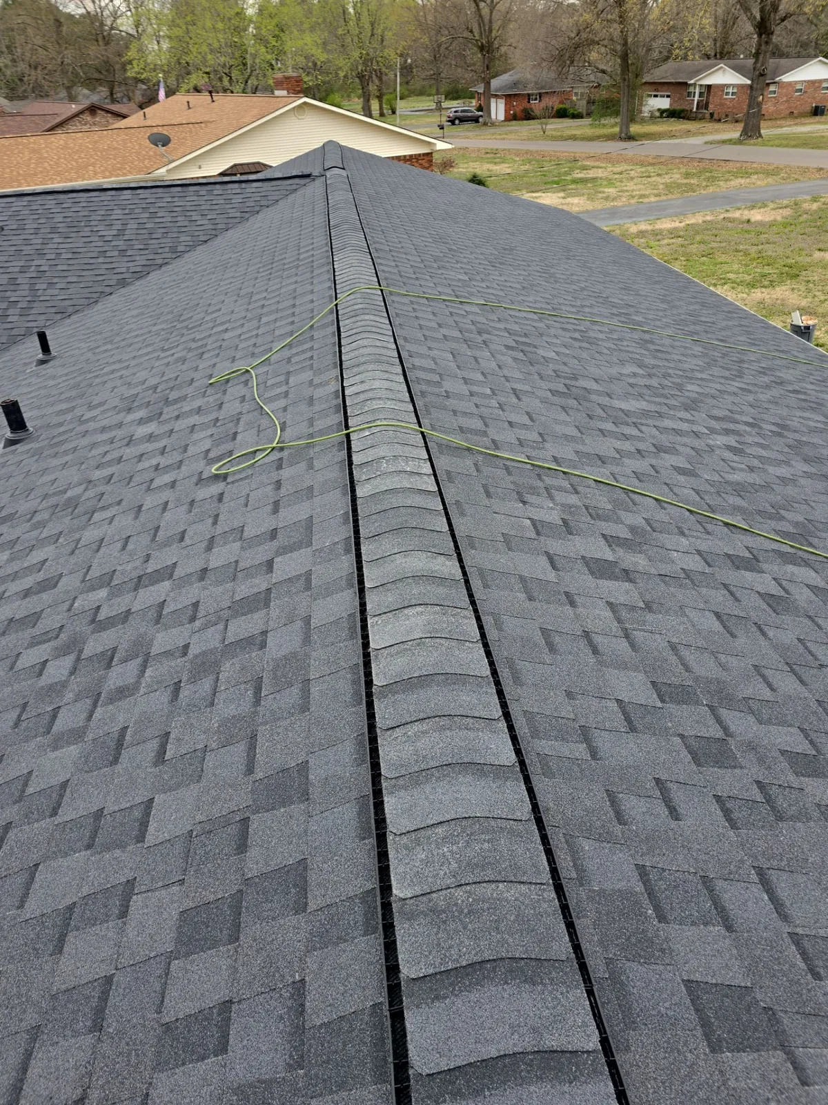 Ridge vent and ridge cap shingles along the peak of the new architectural shingle roof