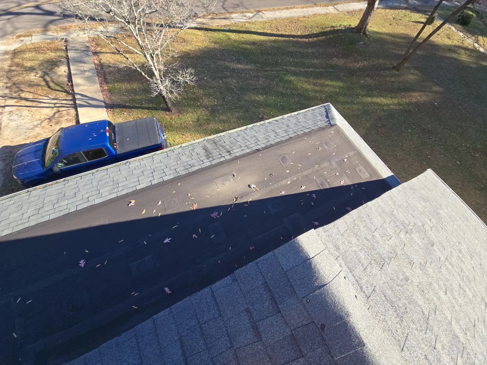 View from the roof of a bungalow in Paris, TN onto its old dark low-slope section between two shingled slopes, before replacement