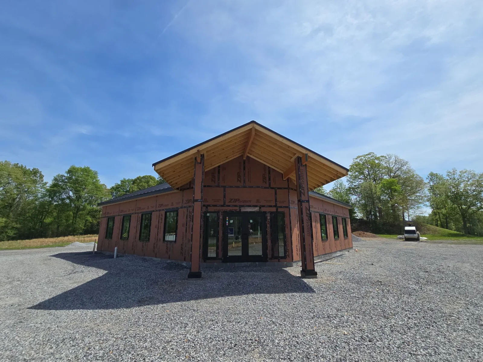 Front of the new building with its standing-seam metal roof carried over a timber canopy above double glass doors