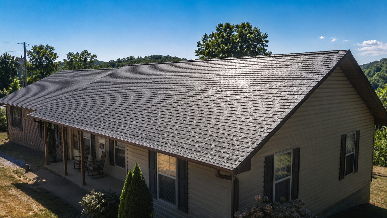 Sun beating down on the dark asphalt shingle roof of a western Kentucky ranch home on a clear summer day